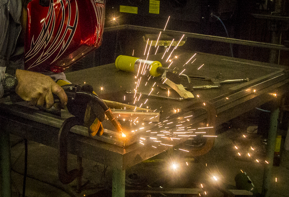 Welder working on a metal table with sparks flying.